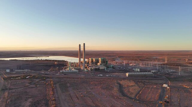 Aerial view of Cholla Power Plant with its tall smokestacks and industrial structures set against a desert landscape at sunset in Joseph City, Arizona, United States.