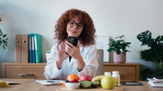 Video of nutritionist woman using smartphone while working with computer in the hospital consultation