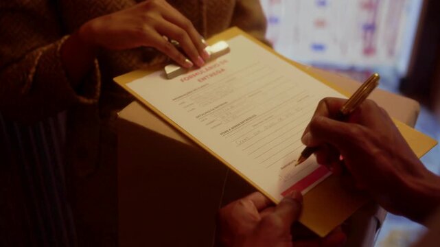 Close up of customer signing a delivery form or official document with a pen, person providing signature for package receipt and successful shipping service in high quality cinematic 4k.