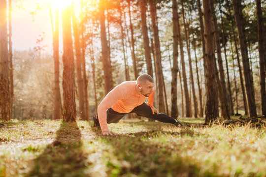 Man doing exercise in the forest during the afternoon with sunlight shining through trees