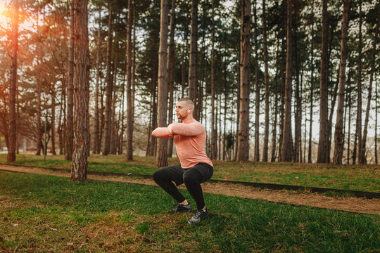 Person exercises by doing squats in a forest area as the sun starts to set on a quiet evening