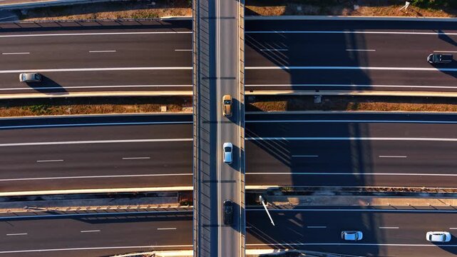 Aerial top view of cars driving on highway under bridge. Top down aerial view of asphalt multi lane highway with cars and shadows from overpass bridge in sunny day.