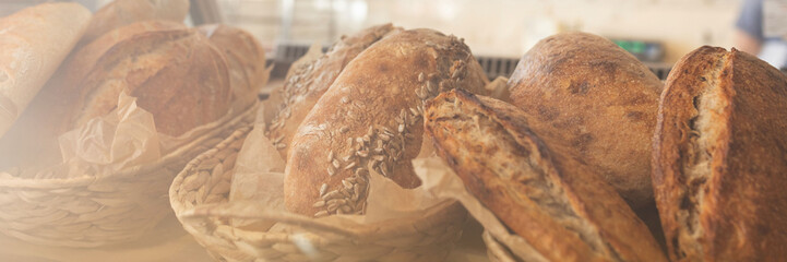 Obraz premium Assortment of fresh artisan bread loaves in wicker baskets, bakery display, wide banner with copy space