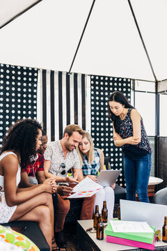 Diverse friends collaborating on laptop and papers indoors