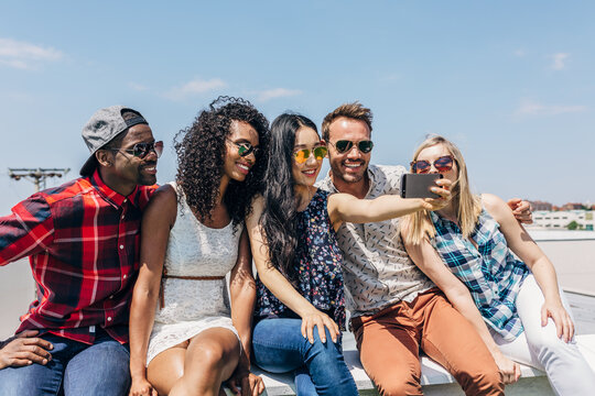 Group of friends taking a selfie on a sunny rooftop