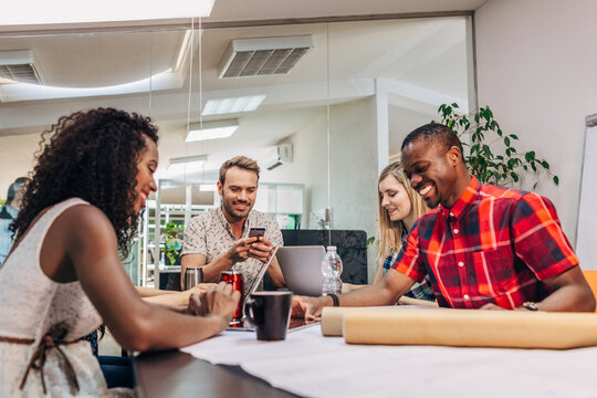 Diverse team meeting in modern office with plans and laptop