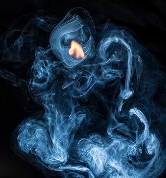 Blue smoke curls around small flame in dark abstract composition.
