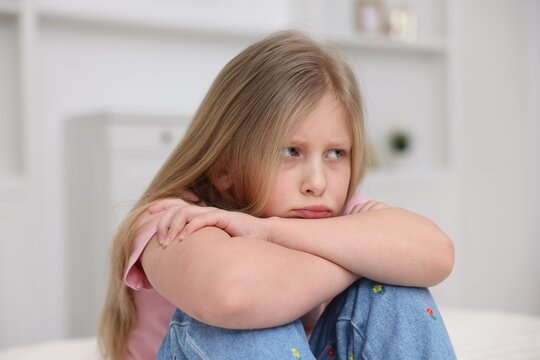 Resentful little girl sitting on floor at home
