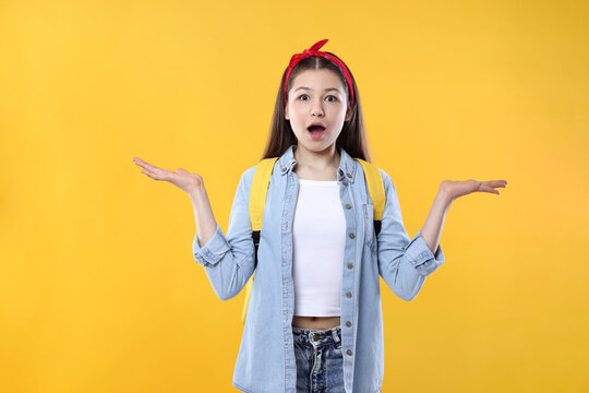 Teenage girl with backpack on orange background