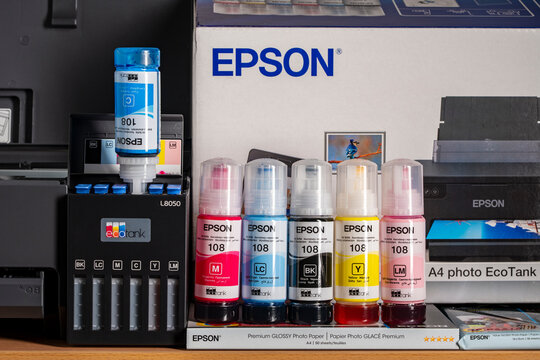 Close up of Epson 108 ink bottles and EcoTank L8050 photo printer. Concept of home printing maintenance and continuous ink supply system setup