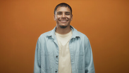 Obraz premium Man looking to side showing face and shoulders in studio wearing light denim jacket and t shirt, subtle smile and direct posture; calm introspection.