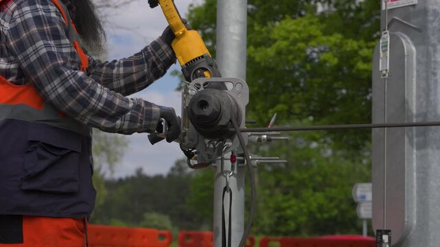 Utility worker operating cable winch on roadside pole