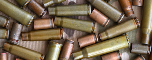 Obraz premium Big amount of shells cartridges from assault rifle bullets on old camouflage fabric