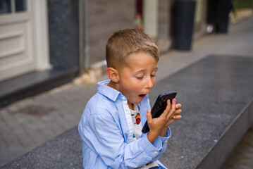 Surprised boy using smartphone outdoors emotional reaction © Ruslan MN