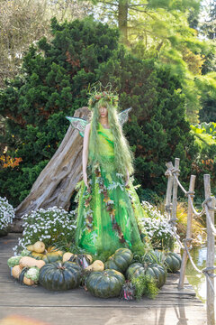 Green forest fairy mannequin standing among pumpkins Prague