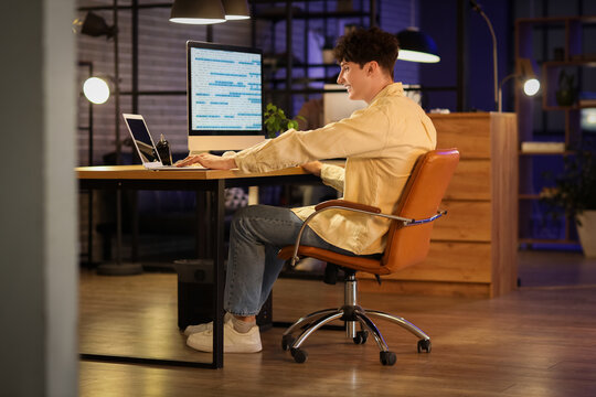 Male programmer working with laptop in office at night