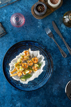 Grilled shrimp skewers with lemon and dill on a blue table