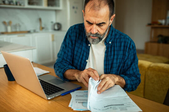 Middle-aged man reviewing bills at kitchen table