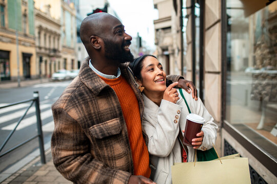 Smiling couple window shopping on city street