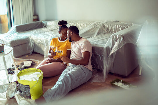 Happy couple toasting during home painting break in living room