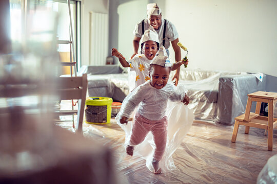 Parent and children playing during living room painting at home