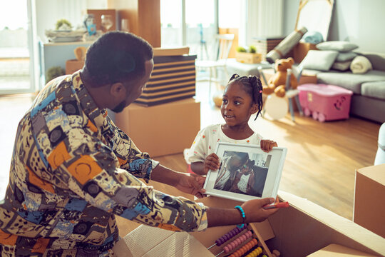 Father and daughter unpacking moving boxes in living room