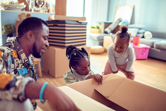 Father and daughters unpacking boxes in new living room