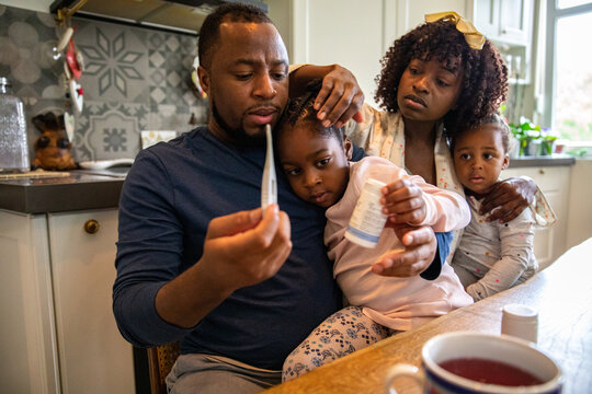Parents check sick child's temperature in kitchen