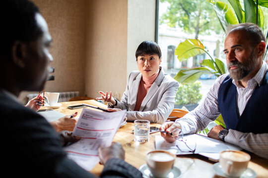 Business colleagues reviewing invoice at coffee shop