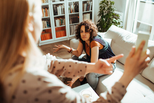 Two women arguing at home in living room