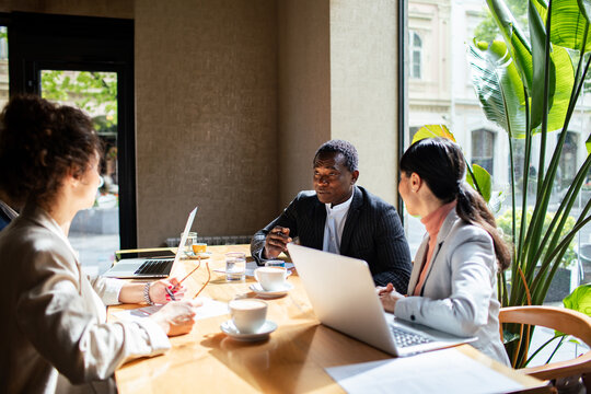 Diverse business team meeting in sunny cafe