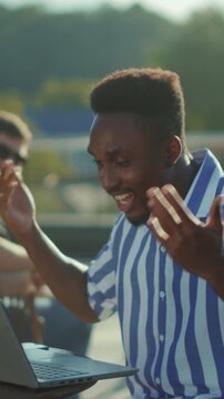 Man enjoys work victory, Man exudes joy and pride after winning remote work challenge among friends in warm sunlight
