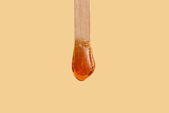 Wooden stick with sugaring paste on yellow background