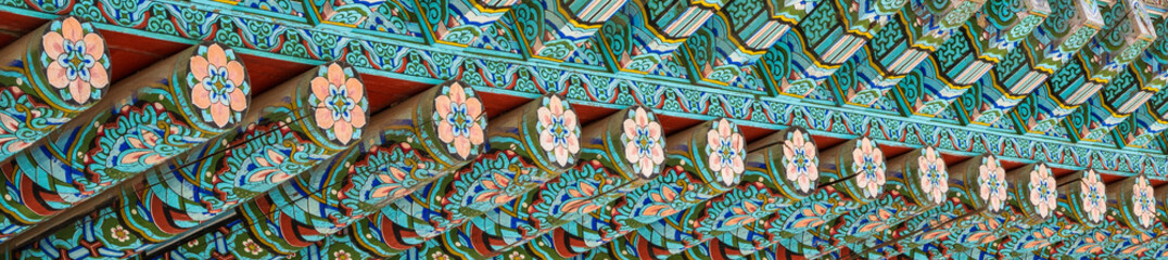 Fototapeta premium Full frame background of traditional Korean Dancheong decorative lotus patterns on wooden temple roof eaves.