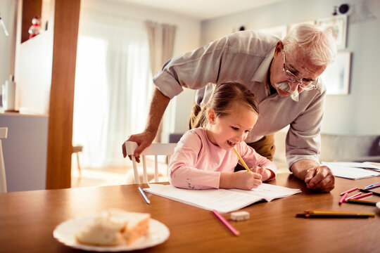 Grandfather helping granddaughter with homework at home