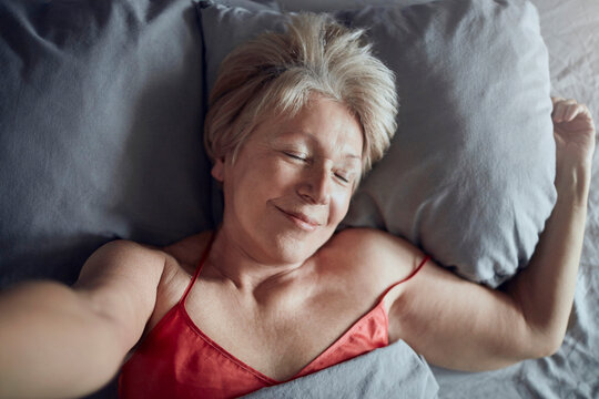 Smiling senior woman resting in bed at home