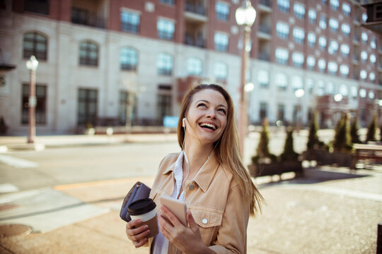 Smiling young woman with coffee and phone on city street