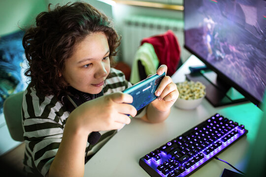 Teen gamer playing mobile game at home desk