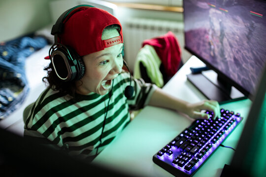 Excited child gamer shouting while playing pc at home