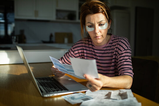 Woman reviewing bills and budgeting at home kitchen table