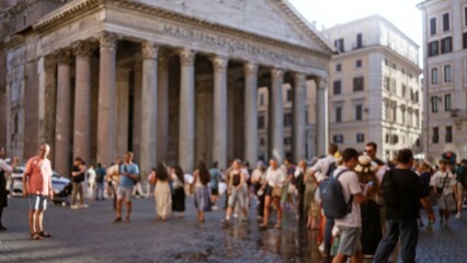 Obraz premium Shallow bokeh of a busy city plaza with defocused classical columns and sunlit cobblestone foreground; background backdrop copyspace calm.