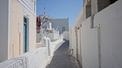 Fototapeta premium Sunlit narrow mediterranean alley with shallow defocused background, whitewashed walls and cobblestone path; background backplate copyspace calm.