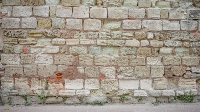 Closeup of weathered stone and brick wall texture, sharp and highly detailed with beige and terracotta tones, building; background copyspace backplate template.