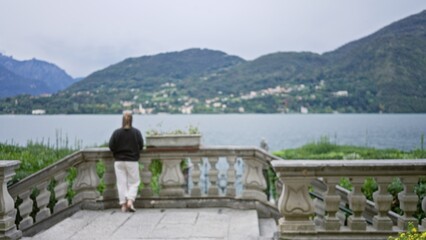 Obraz premium Stone terrace balustrade defocused foreground overlooking lake and misty hills, garden; background backdrop copyspace calm.