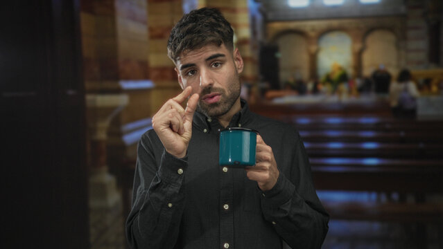 Man pinches fingers to show small amount while holding blue enamel mug at church pew; contemplation.