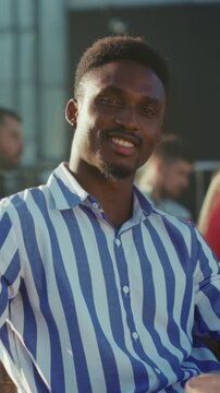 Black male at urban rooftop, Dynamic portrait capturing friendly Black professional on lively rooftop cafe scene