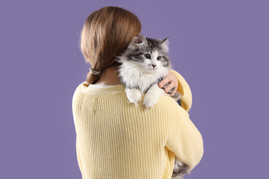 Owner holding cute cat after sterilization on lilac background