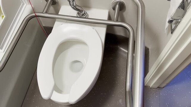 Accessible toilet with support rails in a small restroom, close up, interior facility detail.