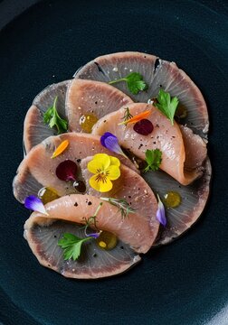 Elegant marinated swordfish carpaccio, thinly sliced and perfectly seasoned, garnished beautifully with vibrant edible flowers and herbs, gourmet, delicate, delicious