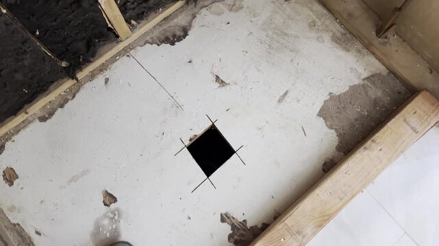 Technological floor opening for utilities or drainage in an unfinished interior during renovation or construction. circling shot